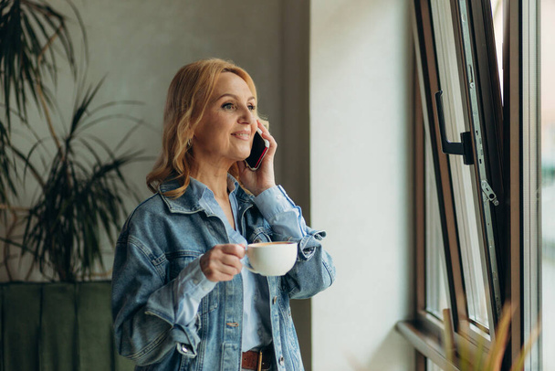 ώριμη γυναίκα μιλάμε τηλέφωνο ένα ποτό καφέ - Φωτογραφία, εικόνα