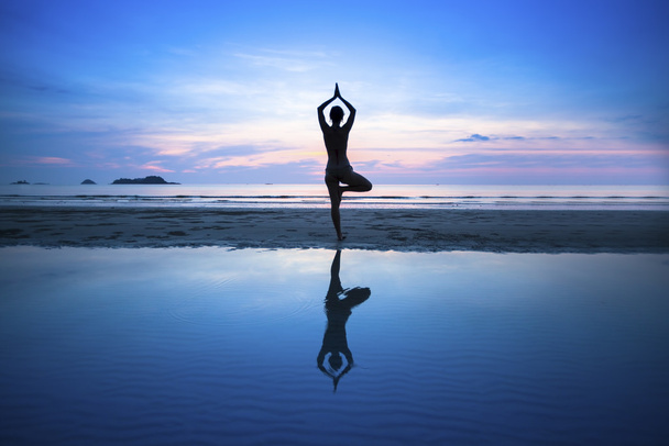 Silhouette Of Woman Standing At Yoga Pose On The Beach During An