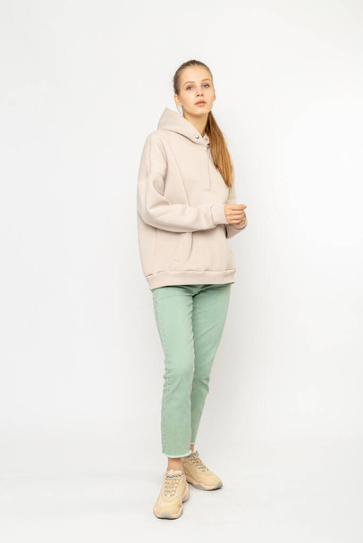 Girl in green cargo pants and beige hoodie isolated on white - 写真・画像