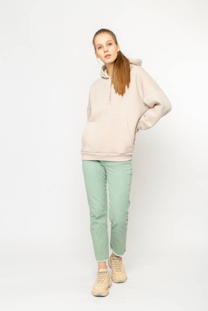 Girl in green cargo pants and beige hoodie isolated on white - 写真・画像