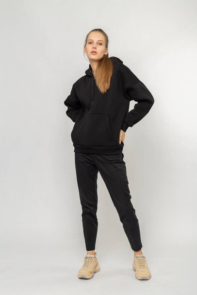 Girl in black cargo pants and black hoodie isolated on white - Фото, изображение