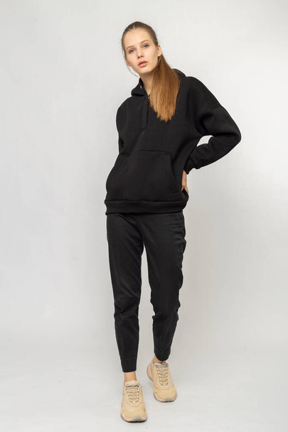 Girl in black cargo pants and black hoodie isolated on white - 写真・画像