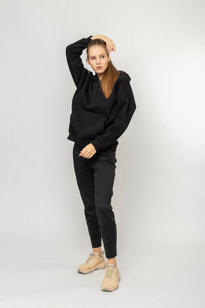 Girl in black cargo pants and black hoodie isolated on white - Φωτογραφία, εικόνα