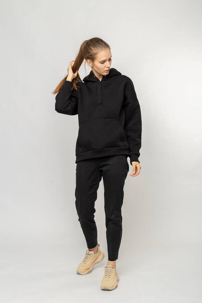 Girl in black cargo pants and black hoodie isolated on white - Valokuva, kuva