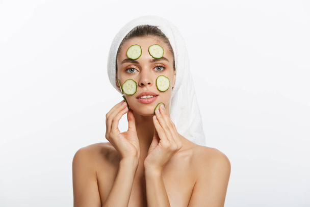 Femme avec masque facial et tranches de concombre dans ses mains sur fond blanc
 - Photo, image