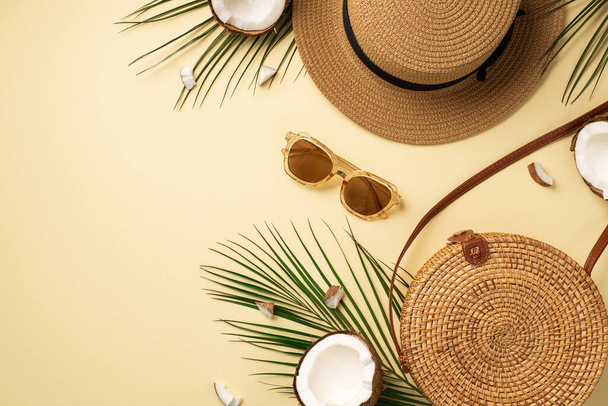 Yaz tatili konsepti. Şapkanın üst görüntüsü, rattan çanta modası geçmiş güneş gözlükleri, hindistan cevizi taneleri ve izole edilmiş pastel bej arka planda palmiye yaprakları. - Fotoğraf, Görsel