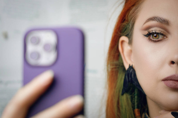 Chica pelirroja toma selfie en la cámara frontal del teléfono inteligente. - Foto, Imagen