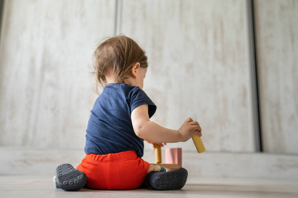 Una niña pequeña niña jugando sola en casa con juguetes educativos creativos de madera copiar espacio atrás ver - Foto, Imagen