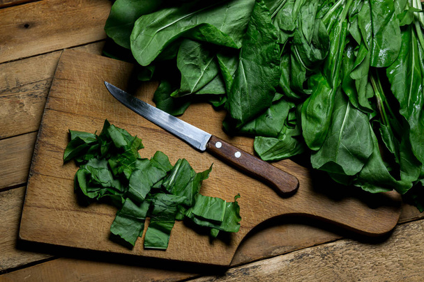 Fresh and chopped sorrel on a wooden board. Vegetarian food. edible greens - Foto, Bild