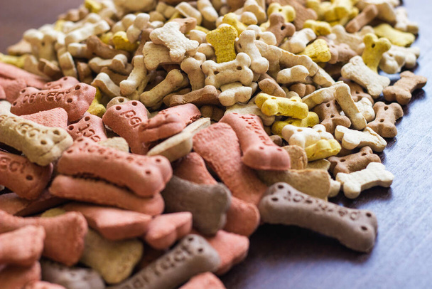 Biscuits colorés savoureux pour chiens sur fond en bois, collations pour chiens. Concept de nourriture sèche saine pour animaux - Photo, image
