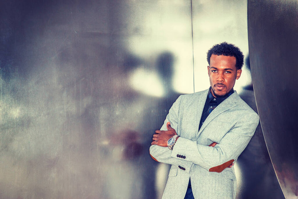 Portret van Afro-Amerikaanse zakenman in New York. Draag grijs patroon blazer, polshorloge, kruisende armen, zwart professional met baard staande tegen zilveren metalen muur. - Foto, afbeelding