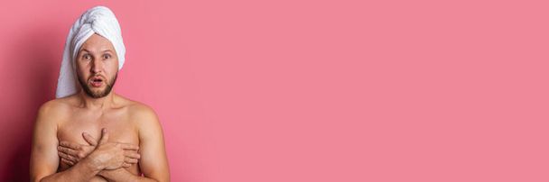 joven desnudo con una toalla en la cabeza, la mano cubre su pecho sobre un fondo rosa. Banner - Foto, Imagen