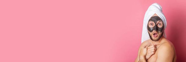 Здивований молодий чоловік з косметичною маскою, оголений позаду на рожевому фоні. Банер. - Фото, зображення