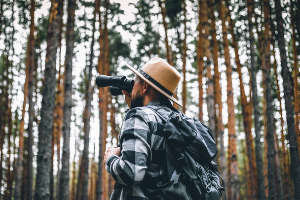 Männlicher Tourist blickt durch Fernglas in den Wald. - Foto, Bild