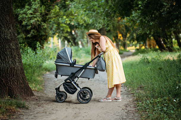 Strollers for Newborns. Keep baby safe in stroller. Mother walking with Newborn baby in stroller in summer park in sunny day - Fotoğraf, Görsel