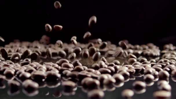 Kávová zrna padající na černé zrcadlo na černém pozadí ve zpomaleném filmu. - Záběry, video