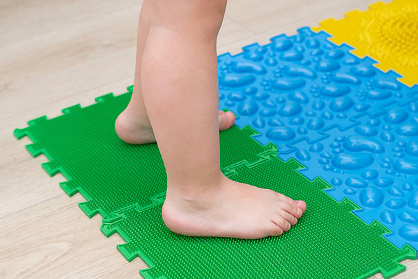 People. Children's small legs stand on multi-colored massage rugs. Health concept. Soft focus. Close-up. - Photo, Image