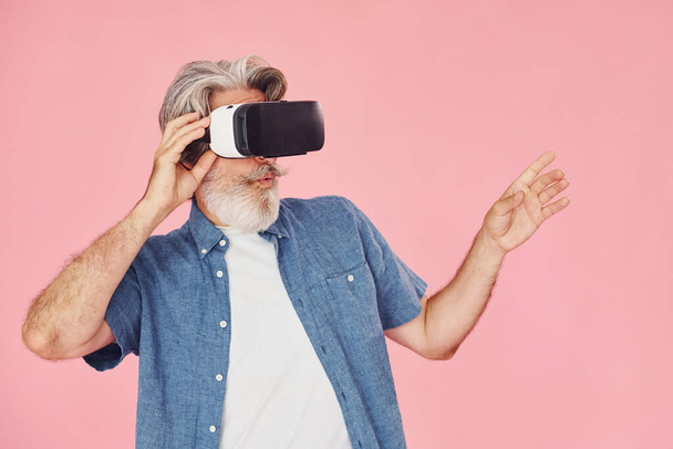 Virtual reality experience. Stylish modern senior man with gray hair and beard is indoors. - Foto, imagen