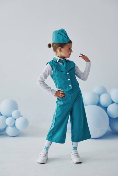Cute little girl in blue stewardess uniform is posing for the camera. - Φωτογραφία, εικόνα