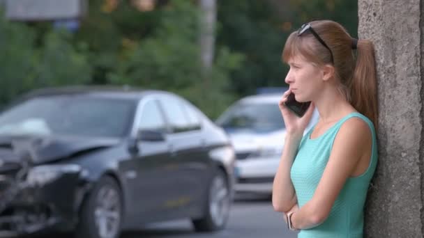 Conductora estresada hablando por teléfono móvil en el lado de la calle pidiendo servicio de emergencia después de un accidente de coche. Concepto de seguridad vial y seguros - Metraje, vídeo