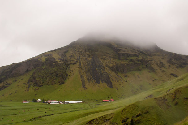 Montaña con cielo nublado y casa abajo
 - Foto, imagen