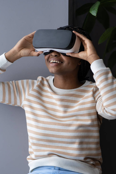 Neşeli genç siyahi bayan modern yenilikçi VR kulaklığı test ediyor. - Fotoğraf, Görsel