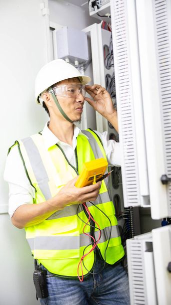 Testeur de travail ingénieur électricien mesurant la tension et le courant de la ligne électrique dans le contrôle de l'armoire électrique. - Photo, image