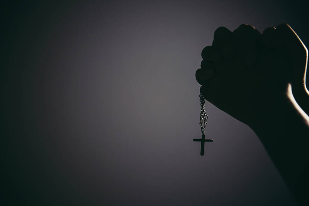 黒と白の女性の手をイメージクロスに対してバラを保持し、教会で神に祈る. - 写真・画像