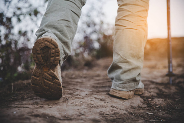 Hiking schoenen in actie op een berg woestijn trail pad. Close-up van mannelijke wandelaars schoenen. - Foto, afbeelding