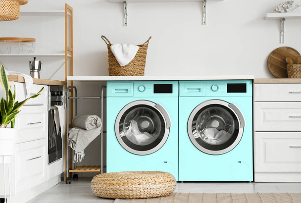 Interieur van lichte keuken met twee turquoise wasmachines - Foto, afbeelding