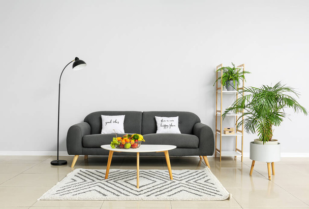 Interiér světlého obývacího pokoje s pohodlnou pohovkou, stolem a ovocným košem - Fotografie, Obrázek