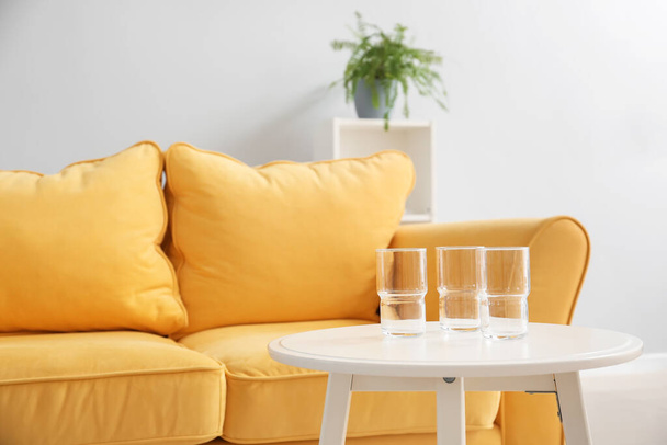Bicchieri sul tavolo vicino divano in soggiorno, primo piano - Foto, immagini