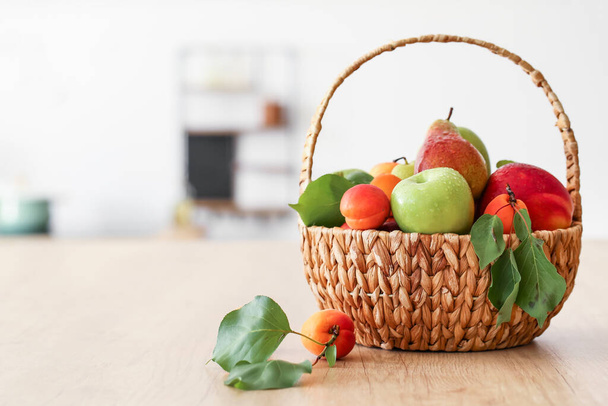 Wicker basket with different fruits on wooden table - Foto, Bild