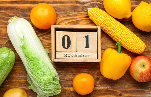 Varie verdure, frutta e dado calendario con data 1 NOVEMBRE su sfondo di legno. Concetto della Giornata mondiale vegana - Foto, immagini