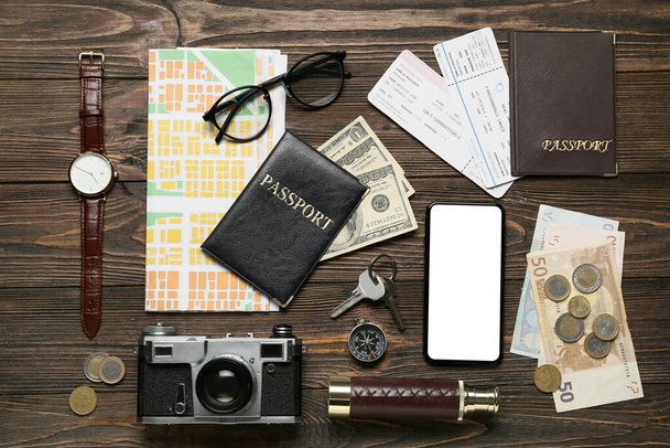 Guide's belongings with mobile phone and city map on dark wooden background - Photo, Image