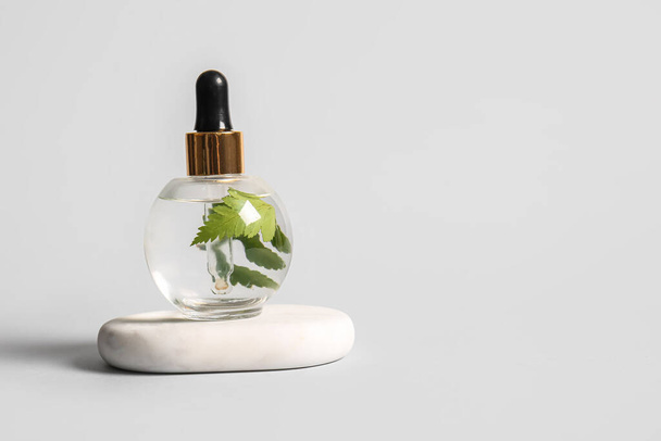 Bottle of natural serum and spa stone on white background - Φωτογραφία, εικόνα