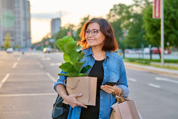 Woman with shopping paper bags, purchased plant walking outdoor - Foto, immagini