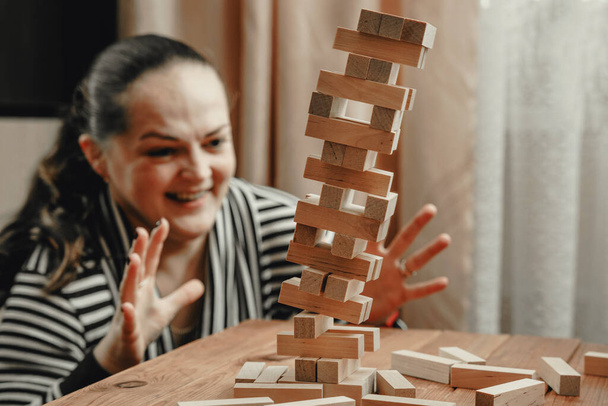 Mom and daughter play a board game, build a tower from wooden blocks. - 写真・画像