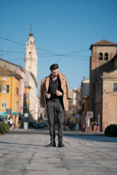 handsome Italian boy walks with coat in the historic center of Parma. High quality photo - Фото, изображение