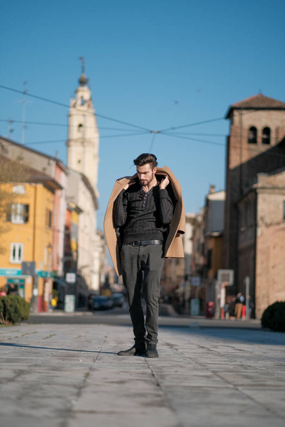 handsome Italian boy walks with coat in the historic center of Parma. High quality photo - Photo, Image