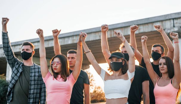 Fists rased high up. Group of protesting young people that standing together. Activist for human rights or against government. - Photo, image