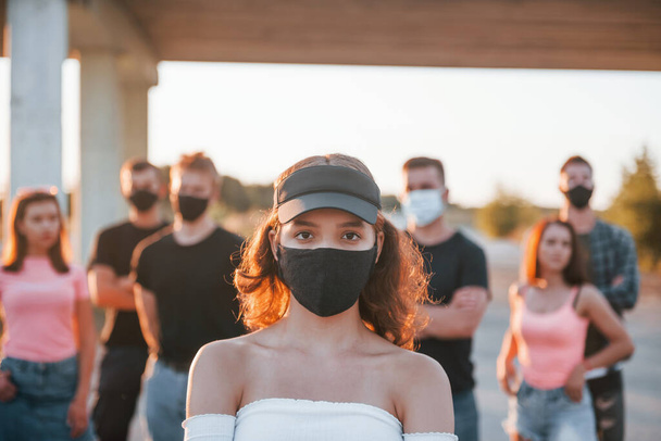 Beautiful girl in mask. Group of protesting young people that standing together. Activist for human rights or against government. - Fotoğraf, Görsel