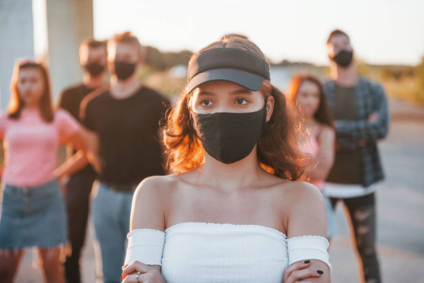 Beautiful girl in mask. Group of protesting young people that standing together. Activist for human rights or against government. - 写真・画像