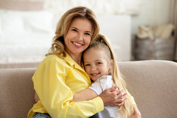 Glücklich mama und kleine tochter umarmung lächelnd to camera indoor - Foto, Bild