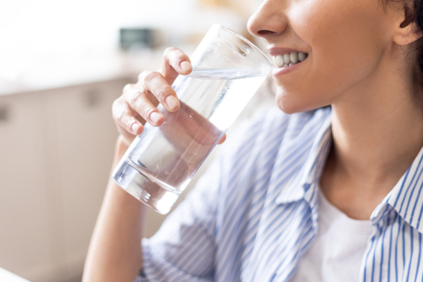 Körperhydrationskonzept. Junge Dame genießt Mineralwasser, durstige Frau trinkt erfrischende Flüssigkeit aus Glas - Foto, Bild