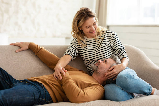 Aimer le couple moyen-âge se détendre sur le canapé à la maison - Photo, image