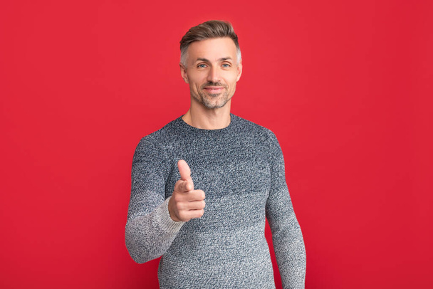 smiling man in sweater point finger on red background, lifestyle - Zdjęcie, obraz