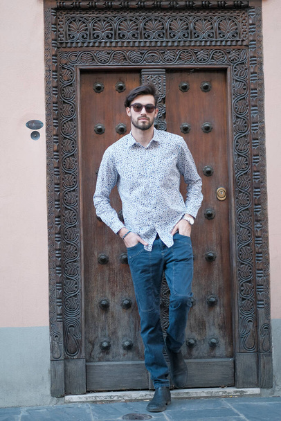 bonito italiano cara posa na frente de uma antiga porta em uma camisa. Foto de alta qualidade - Foto, Imagem