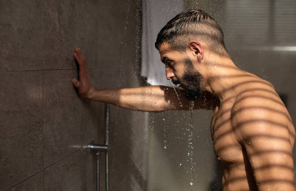 Komea nuori kaveri ottaa kuuma suihku kylpyhuoneessa - Valokuva, kuva