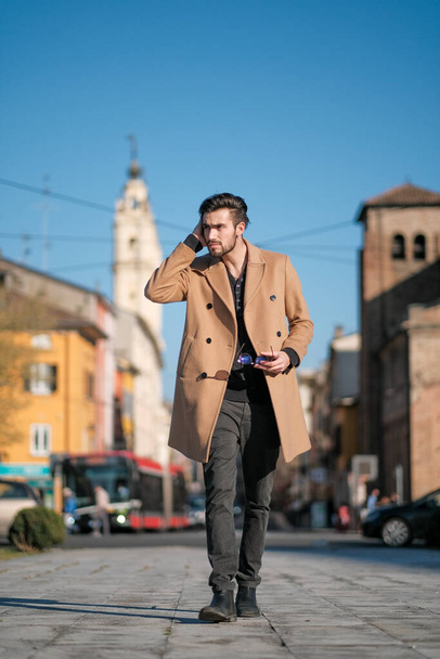 ハンサムなイタリアの少年はパルマの歴史的な中心部にコートを着て歩きます。高品質の写真 - 写真・画像